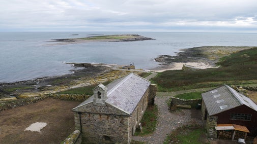 View of St Cuthbert's chapel from above, with the sea beyond.